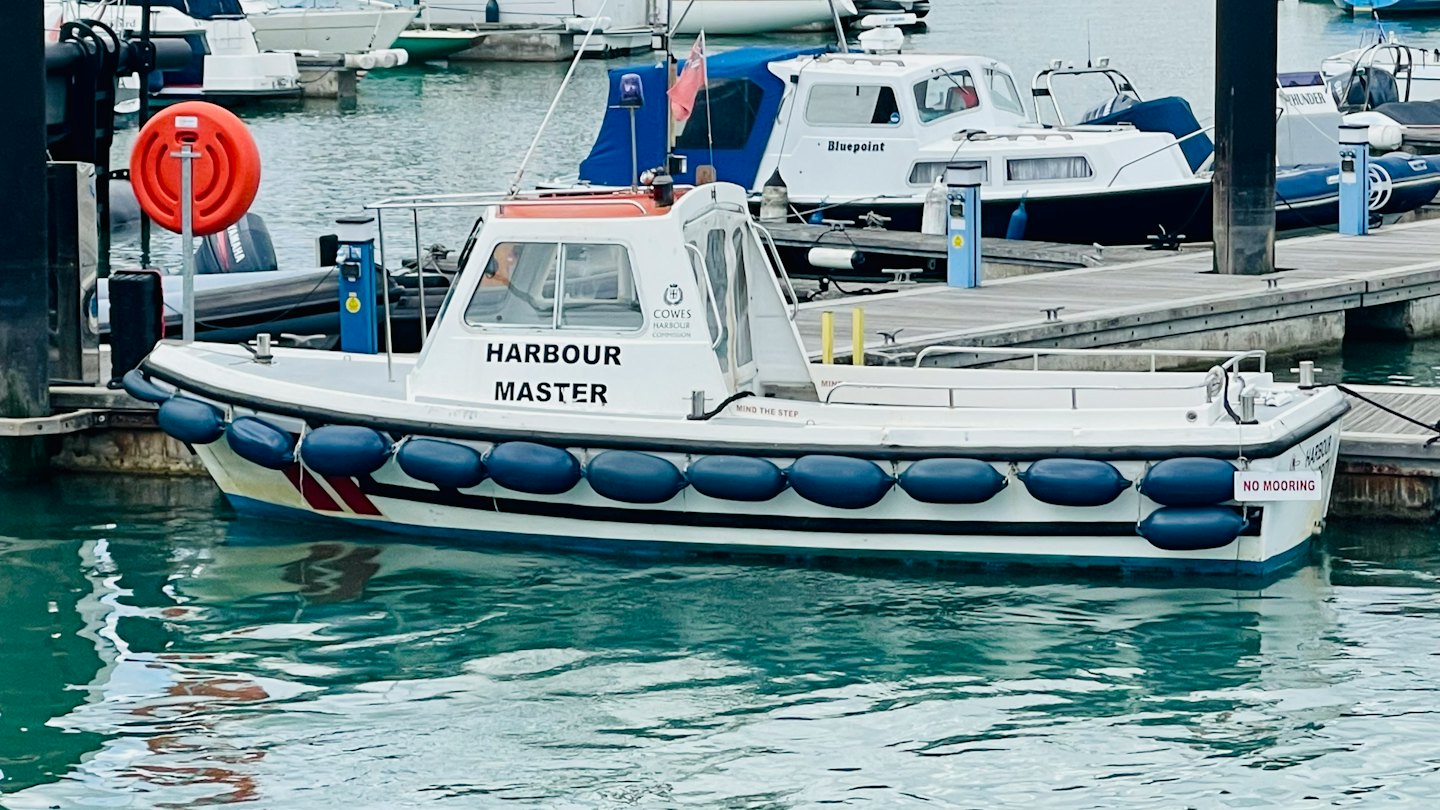 Una barca del capitano del porto bianca attraccata accanto a un salvagente rosso.